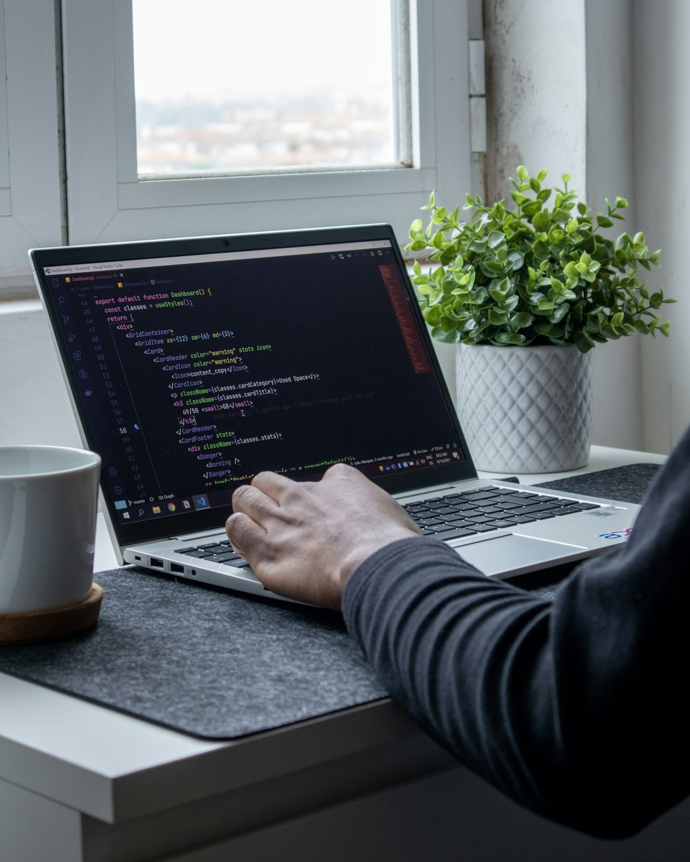 A developer working on a laptop beside a window